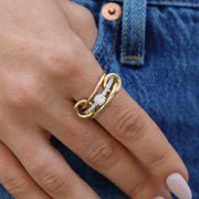 Gold ring with diamonds on a finger against a denim background